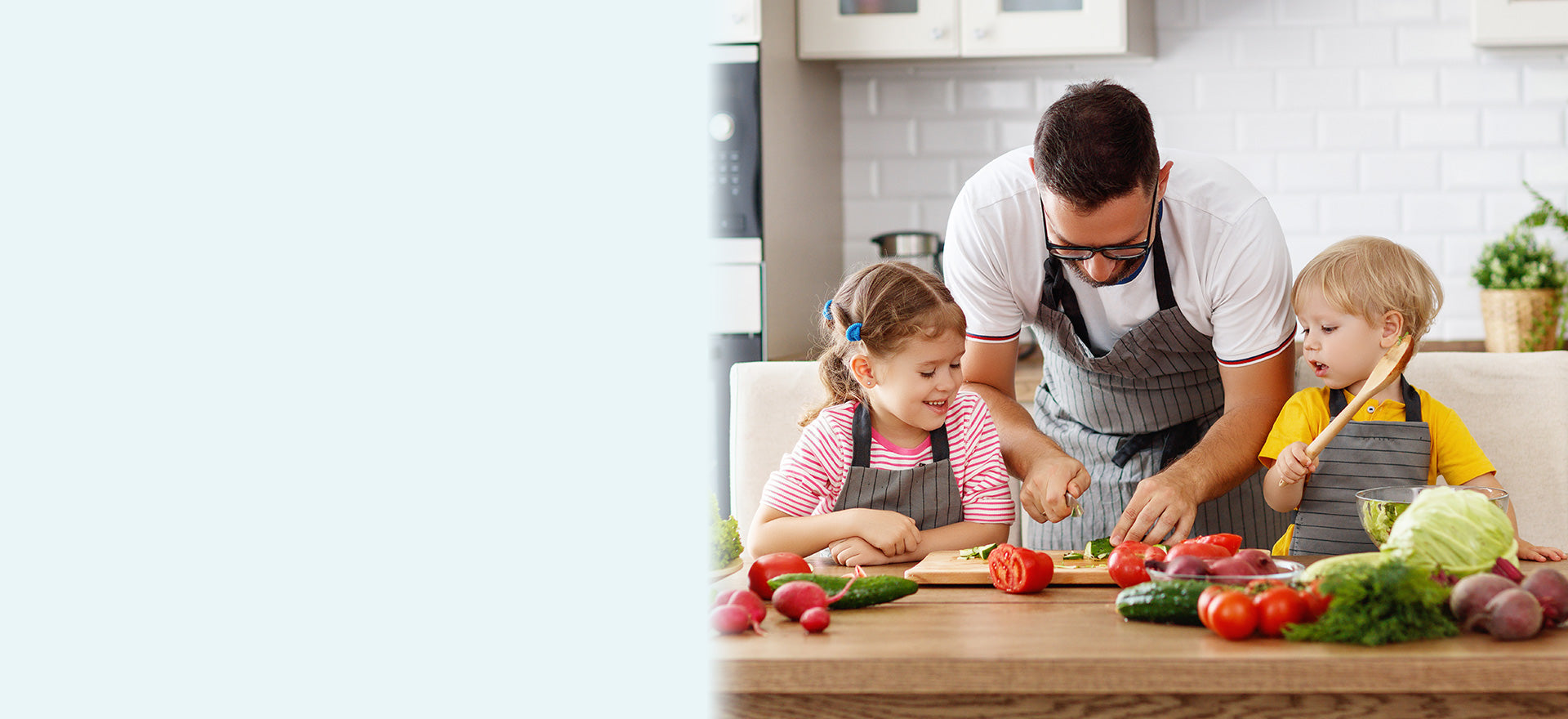 Family cooking together in kitchen with fresh vegetables.