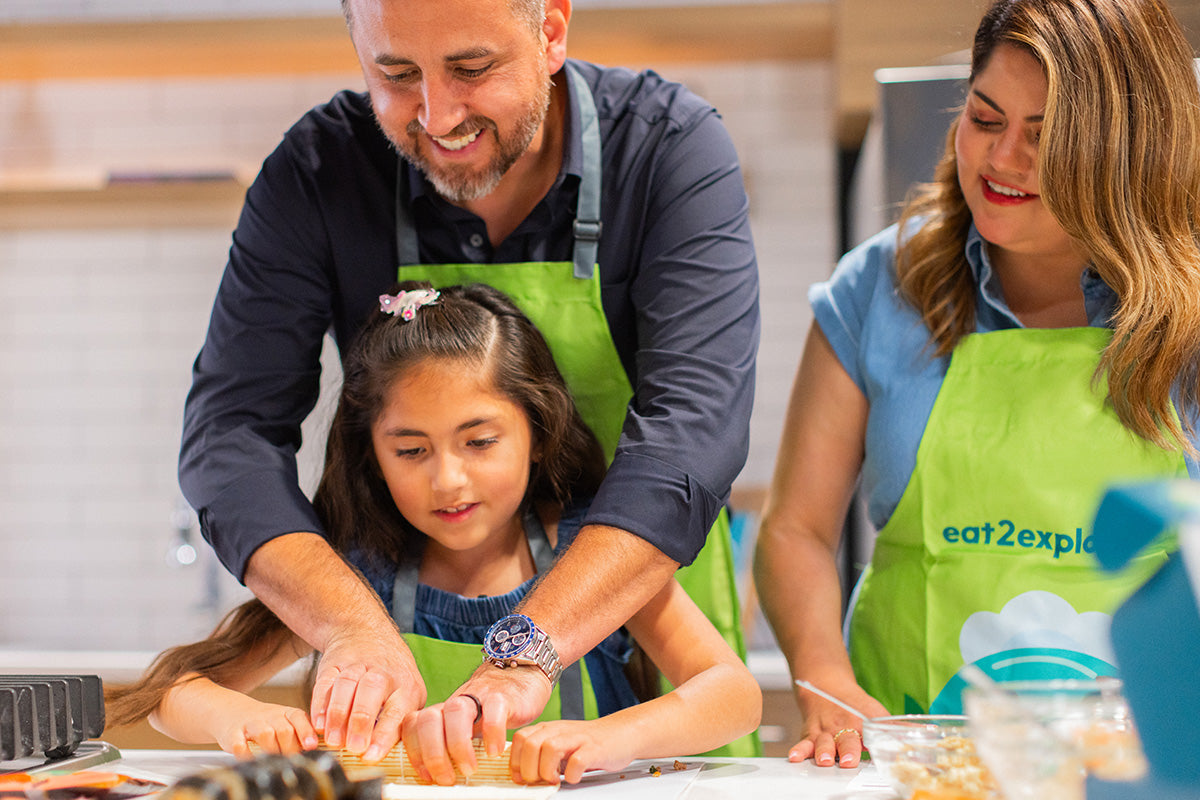 Family cooking activity in kitchen with aprons.