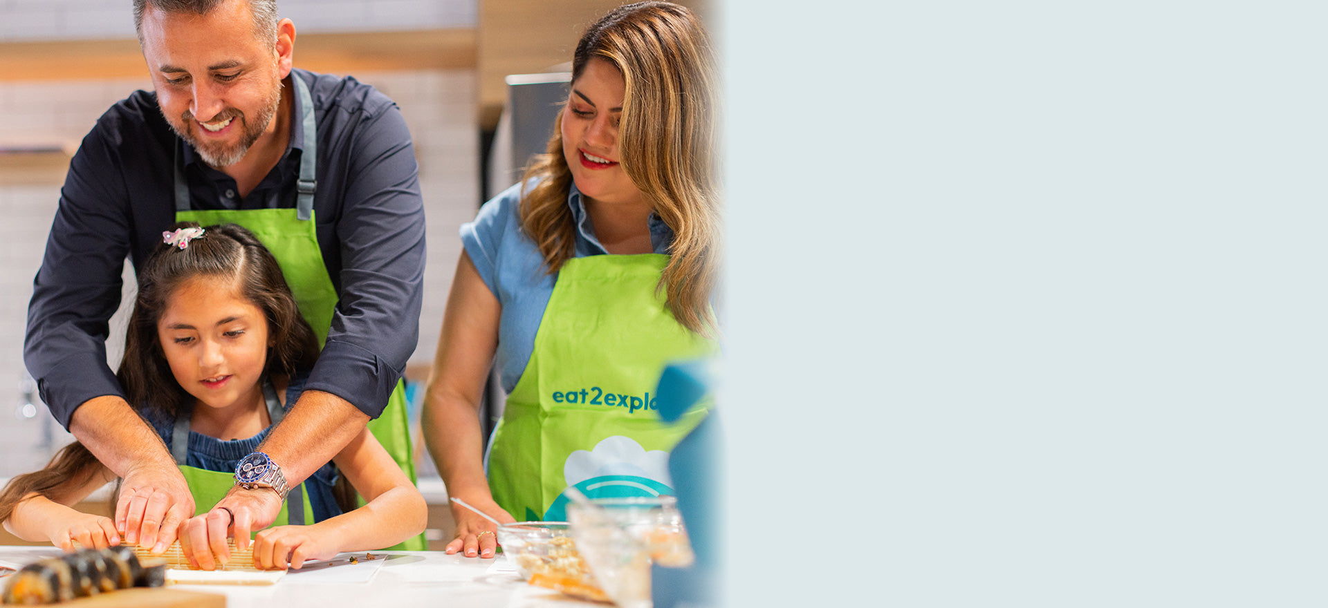 Family cooking together wearing green aprons