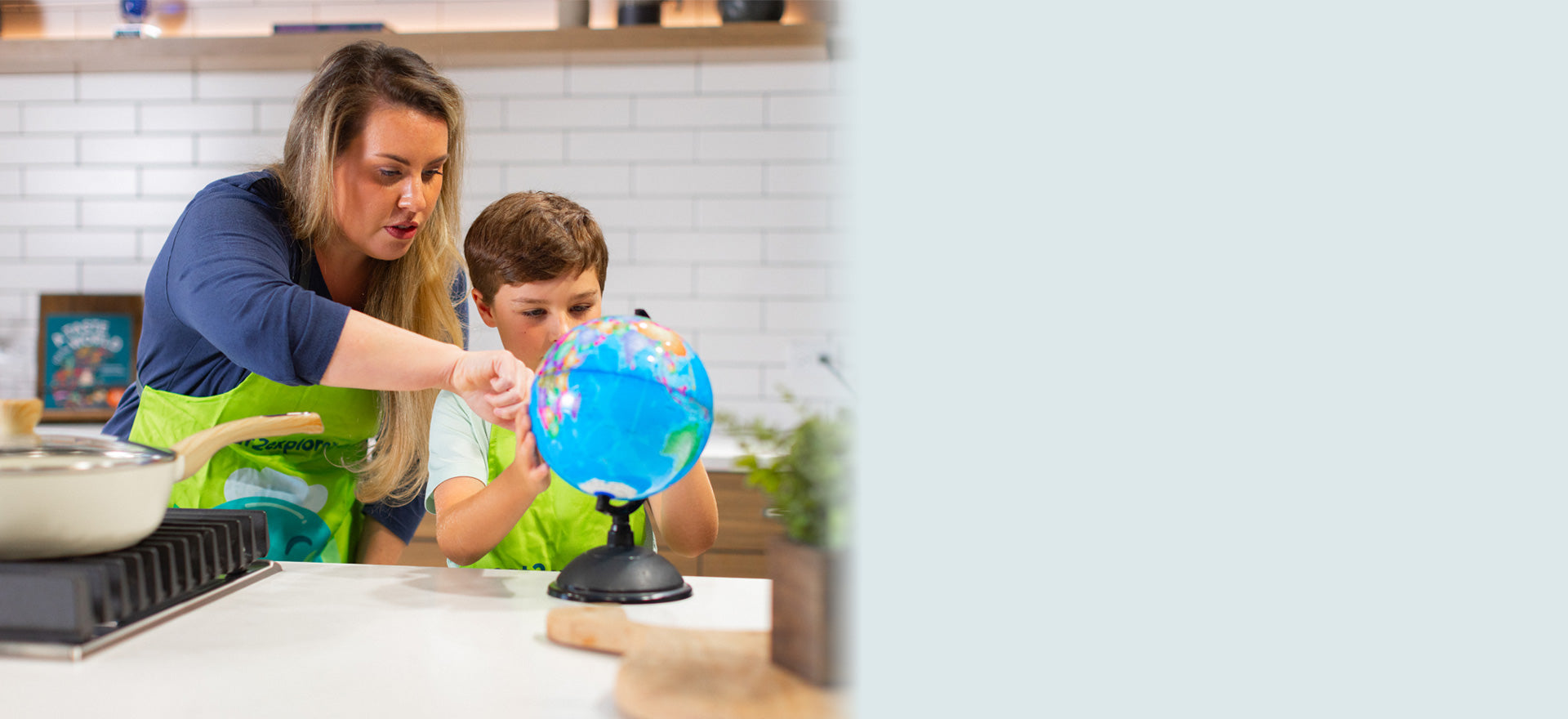Mother teaching child with globe in kitchen