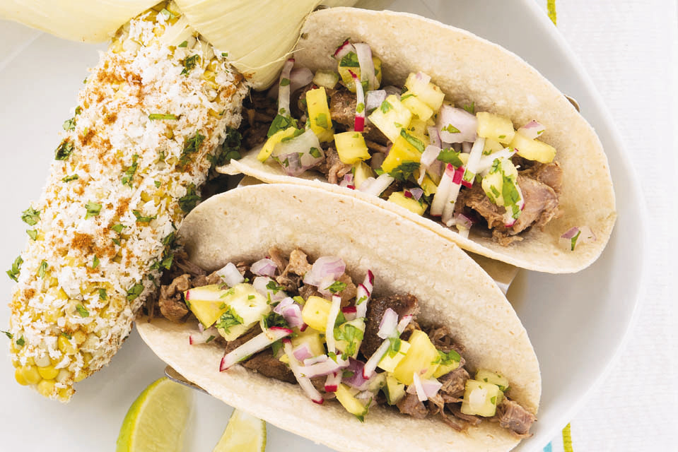 Tacos with pineapple salsa and elote corn on plate