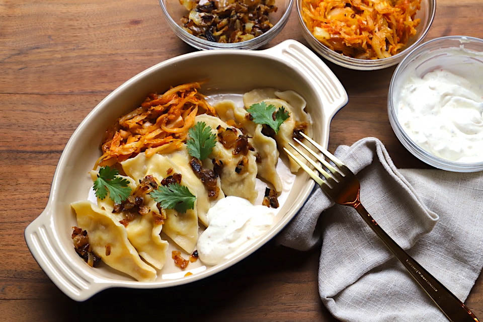dumplings with sauerkraut and sour cream on wooden table