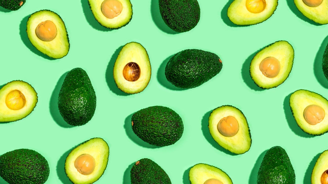 whole and sliced avocados on a green background