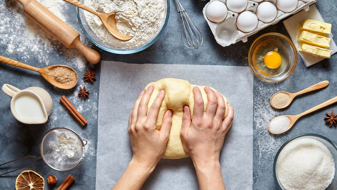 person kneading dough and ingredients for bread