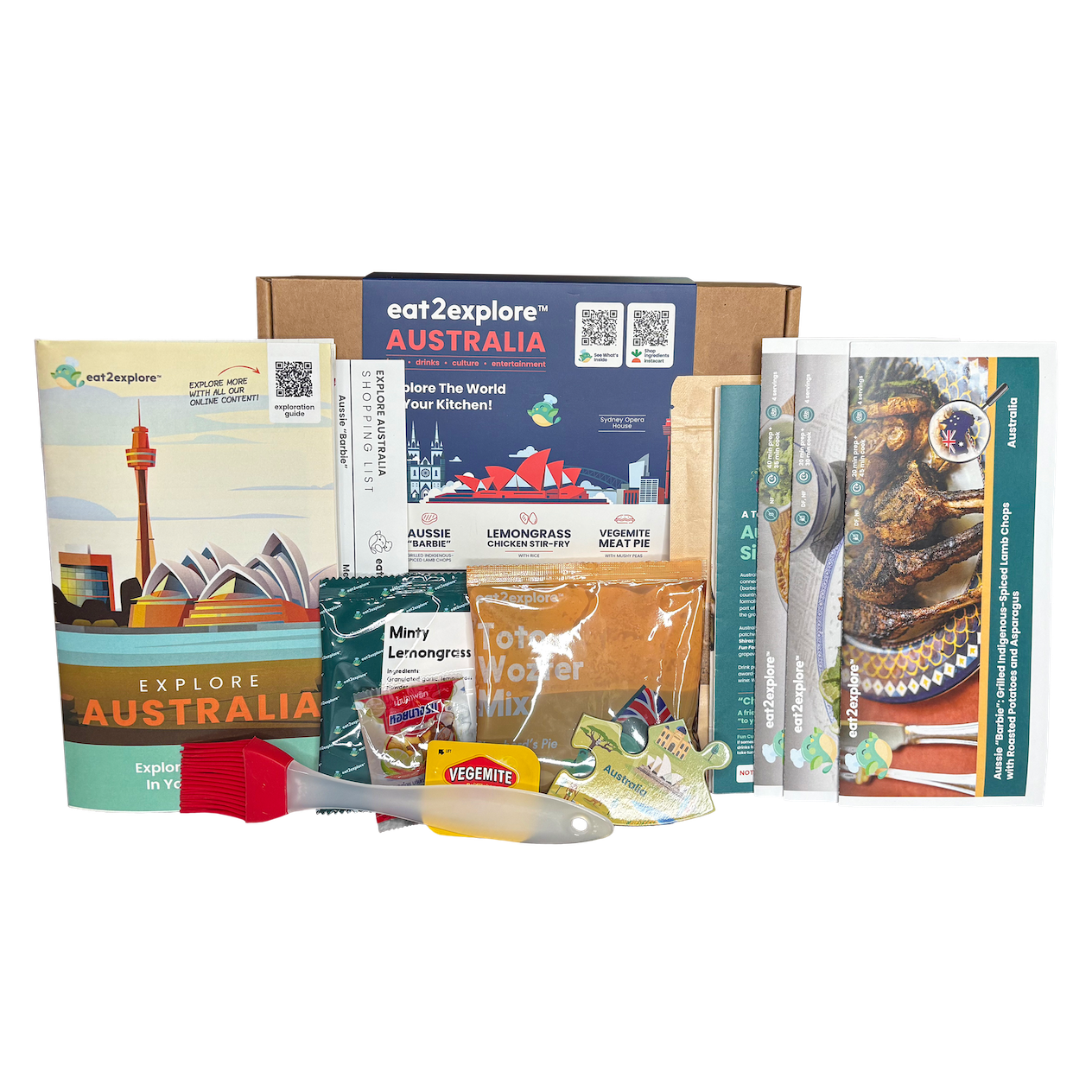 A curated travel food and activity kit for Australia displayed against a solid white background. The kit includes a cardboard box, a colorful guidebook, a small activity sheet, several packaged food items, and a small red-and-white tool.