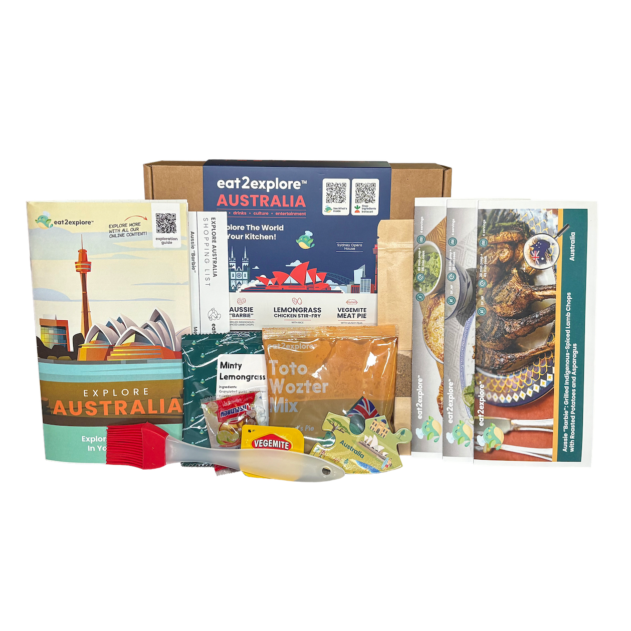 An eat2explore Australia travel experience kit displayed on a white background, containing a cardboard box, a guidebook, a map, a recipe card, a packet of Toto Vozer mix, a packet of Marmot Energy Gummies, and other travel accessories.