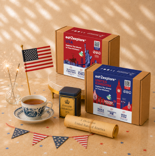 eat2explore USA and United Kingdom themed tea boxes with a cup of tea and American flag on a wooden surface.