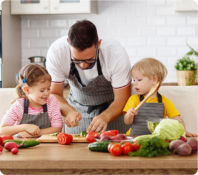Man and two children in aprons preparing vegetables in a kitchen
