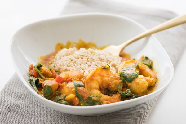 White bowl with shrimp curry and rice on a white background