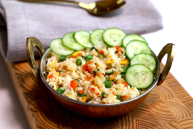 Bowl of fried rice with vegetables and cucumber slices
