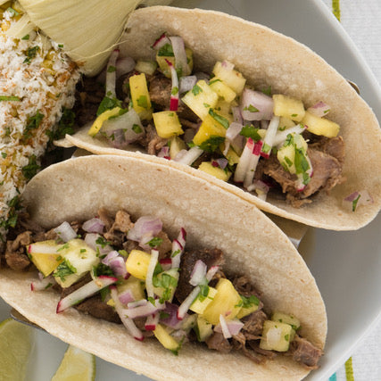 tacos with pineapple salsa and elote corn on plate